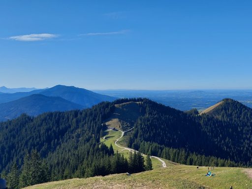 Blick auf hügelige Landschaft mit grünen Wäldern und klarem Himmel.